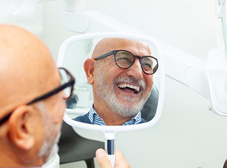 Man with black glasses smiling in reflection in mirror