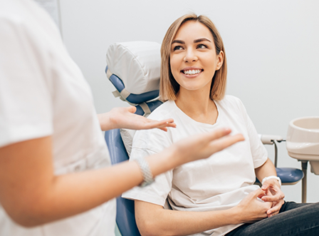 Woman in dental chair looking up at dentist smiling