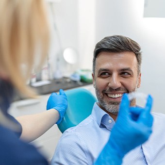 Smiling patient looking at dentist holding aligner