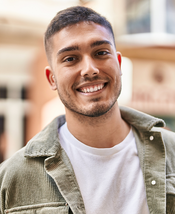 Man with white shirt and beige jacket smiling