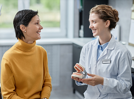 Female dentist talking with female patient in yellow shirt