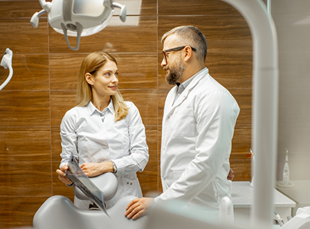 Dentist and dental team member having discussion next to treatment chair