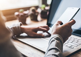 Typing on laptop while looking at phone