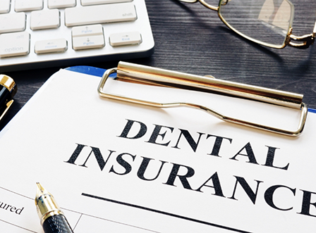 Dental insurance form on clipboard on busy desk