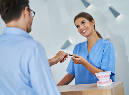 Handing credit card to dental team member