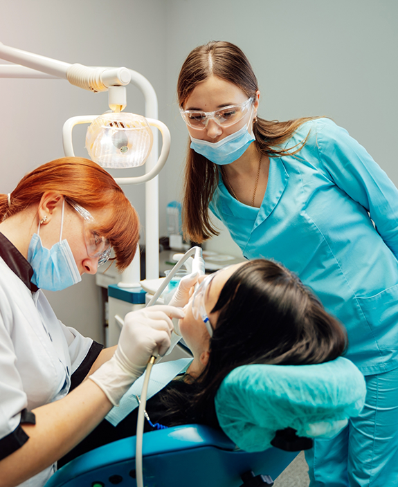 Female dentist and team member treating patient