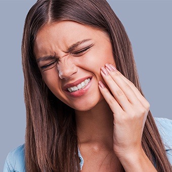Grimacing woman holding her jaw in pain