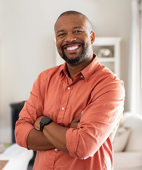 Man in orange button up shirt smiling with dental implants in Austin