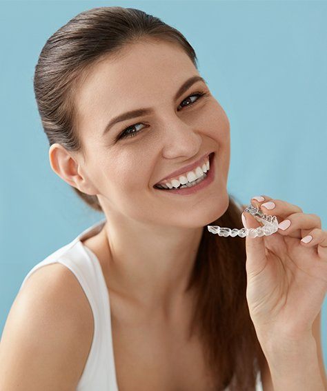 Smiling woman holding Invisalign tray