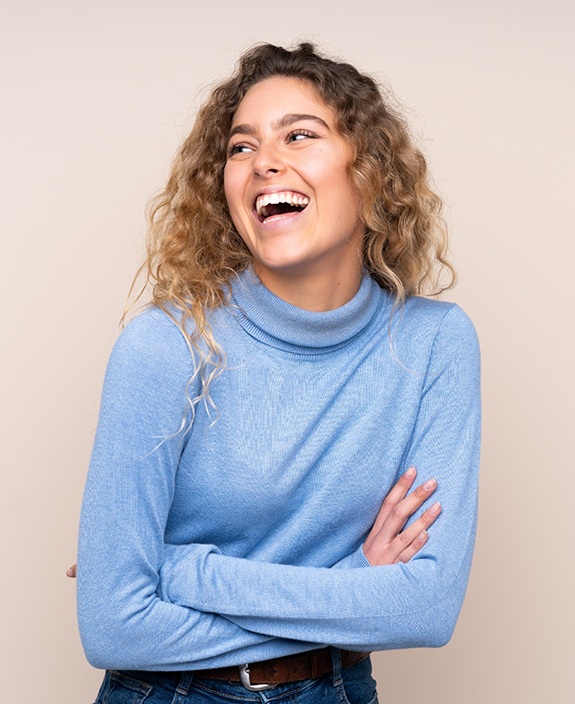 Woman in blue sweater smiling with arms folded