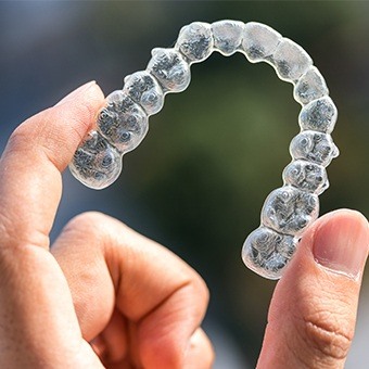 Hand holding an Invisalign tray