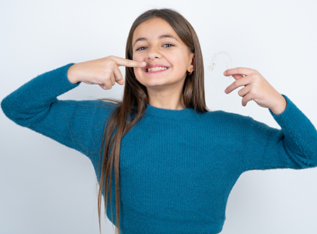 Smiling woman with blue shirt smiling while pulling up lips