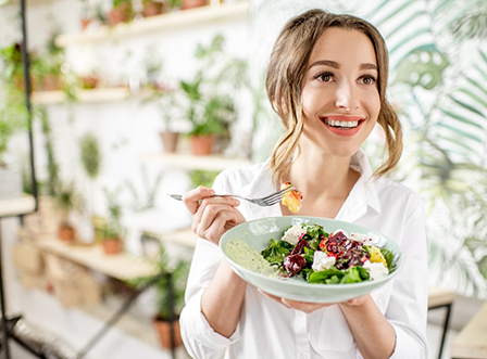 Woman in white shirt eating a salad