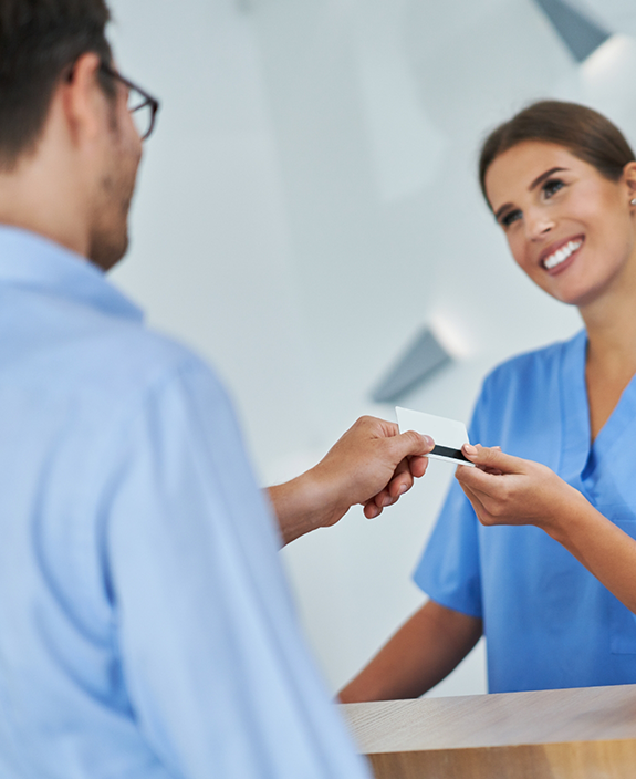Handing credit card to female dental team member