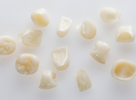 Numerous dental crowns on a white surface