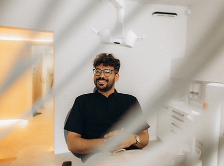 Patient with black glasses smiling in treatment chair