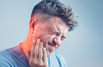 Man holding the side of his jaw in pain