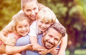 Mother father and two kids laughing together outdoors after dental services in Austin