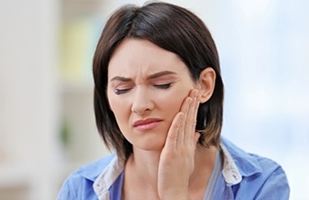 Woman holding her cheek in pain