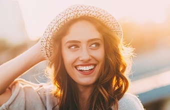 Smiling woman wearing sunhat outdoors on sunny day