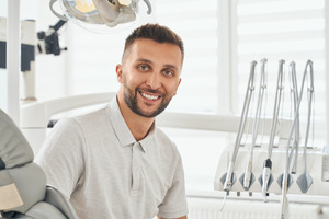 Man in collared shirt sitting in dental chair and smiling